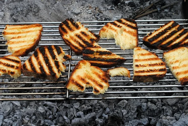 Slices of grilled bread rubbed with garlic on a barbecue — Stock Photo, Image