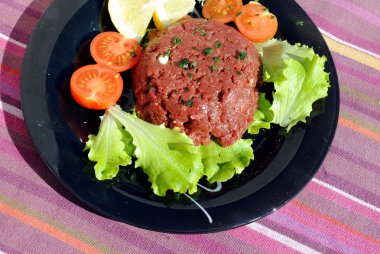 siyah bir yemek üzerinde sebze ile çiğ kıyma