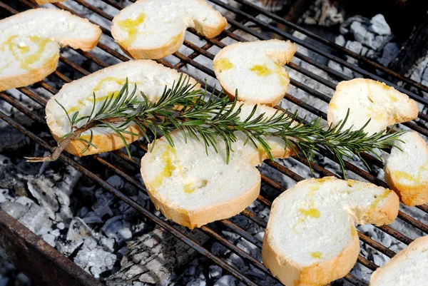 Slices of bread and rosemary on a barbecue — Stock Photo, Image