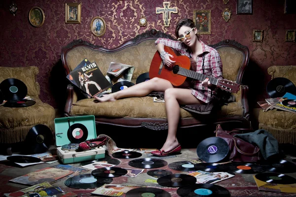 Eski bir kanepede gitar çalan kız