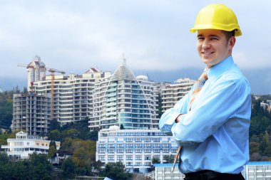 Young architect wearing a protective helmet standing on the moun clipart