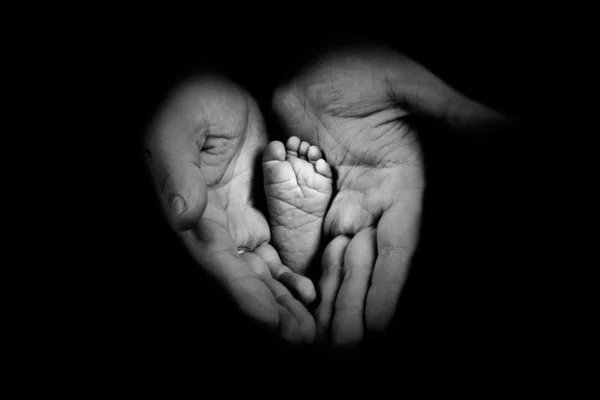 Babys pies en las manos del padre en el fondo monocromo — Foto de Stock