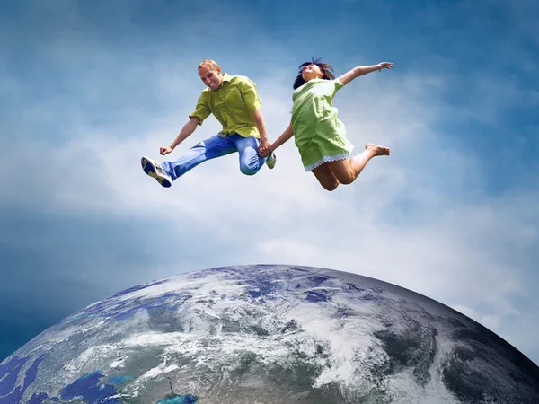 Веселая пара в прыжке через планету Земля — стоковое фото