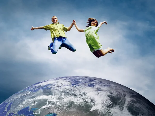 Веселая пара в прыжке через планету Земля — стоковое фото