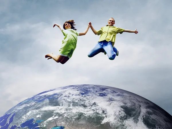 Pareja divertida en salto sobre el Planeta Tierra — Foto de Stock