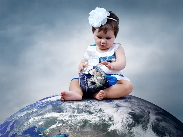 Enfant assis sur la planète Terre avec des globes dans les mains — Photo