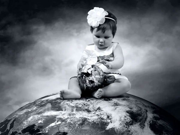 Kind sitzt mit Globen in der Hand auf dem Planeten Erde — Stockfoto