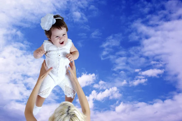 Enfant en blanc dans les mains de la mère sous fond de ciel — Photo