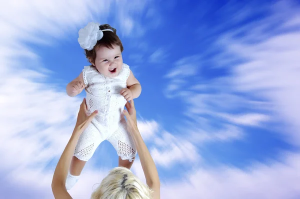 Enfant en blanc dans les mains de la mère sous fond de ciel — Photo