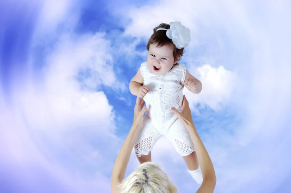 Dítě v bílém v rukou matka pod pozadí oblohy — Stock fotografie
