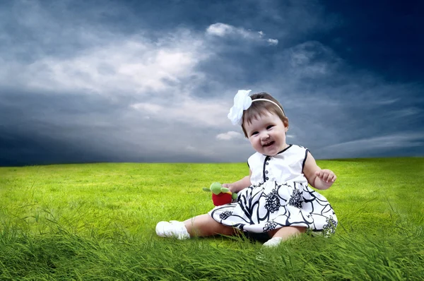 Štěstí holčička seděli na trávě v poli — Stock fotografie