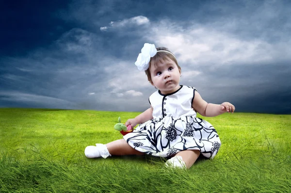 Szczęście dziewczynka siedzi na trawie w dziedzinie — Zdjęcie stockowe