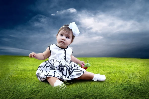 Lycka baby flicka sitter på gräset i fältet — Stockfoto