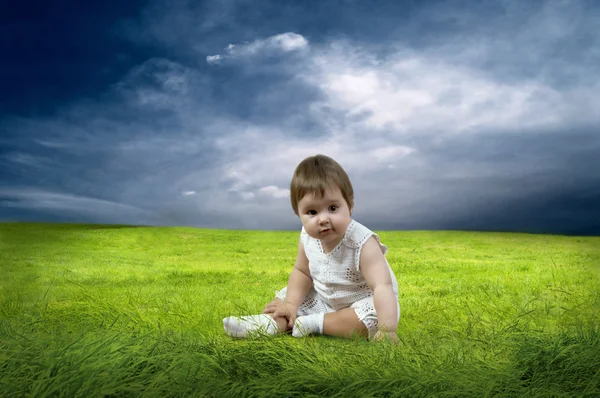 Geluk babymeisje, zittend op het gras in veld — Stockfoto
