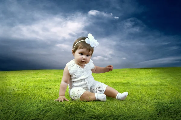 Szczęście dziewczynka siedzi na trawie w dziedzinie — Zdjęcie stockowe
