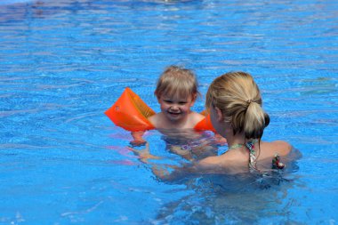 Girl with her mother in the swimming pool clipart