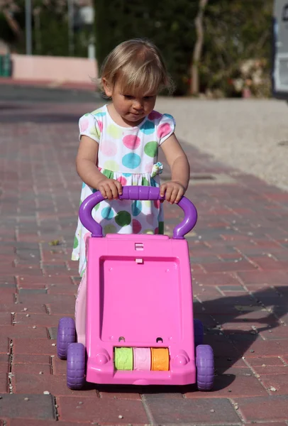 Yürümeye başlayan çocuk kız iterek oyuncak arabası — Stok fotoğraf