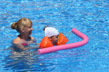 Girl with her mother in the swimming pool clipart