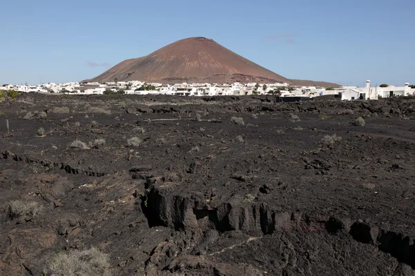 Tipico paesaggio di Lanzarote, lava, villaggio e vulcano — Foto Stock