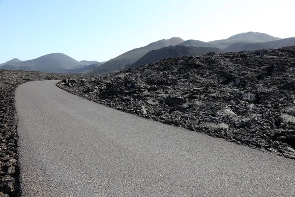 Straße durch ein Lavafeld die montanas del fuego auf kanarische insel lanzarote — Stockfoto