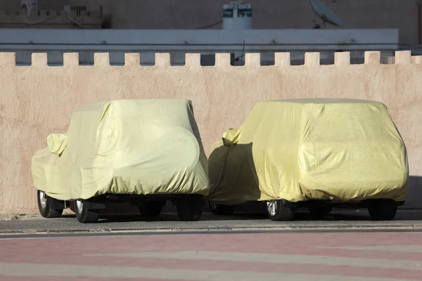 Krytá auta zaparkovaná u zdi. Ajman, Spojené arabské emiráty — Stock fotografie