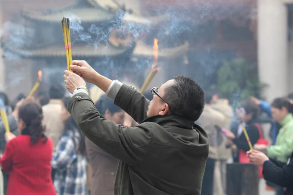 Persona de oración con palos de incienso en el templo budista en Shanghai, China —  Fotos de Stock