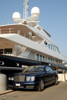 Bentley convertible parked in front of a luxury yacht in Saint Tropez, France clipart