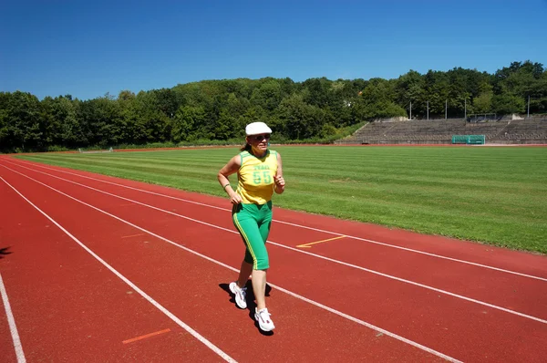 Aktivní senior žena běhat na stadionu — Stock fotografie
