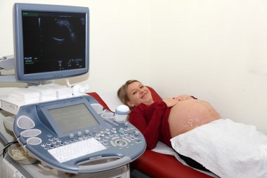 Happy pregnant woman at the ultrasound examination clipart