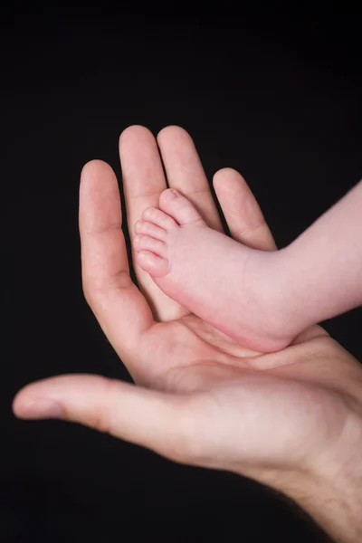 Pé recém-nascido em uma mão adulta — Fotografia de Stock