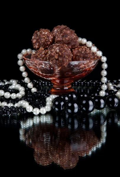 Assortiment de bonbons au chocolat dans un bol en verre sur fond noir — Photo