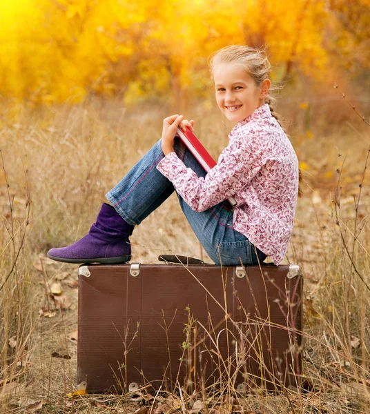 Девочка-подросток читает книгу в красивом осеннем лесу — стоковое фото