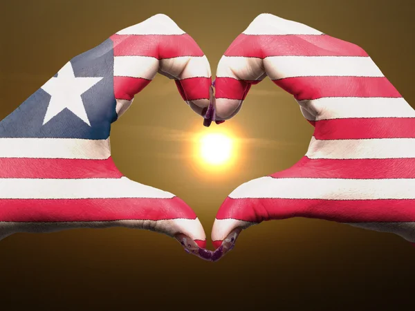 Coração e amor gesto por mãos coloridas na bandeira da Libéria durante b — Fotografia de Stock