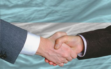 Businessmen handshake after good deal in front of argentina flag clipart