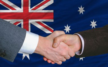 Businessmen handshake after good deal in front of australia flag clipart