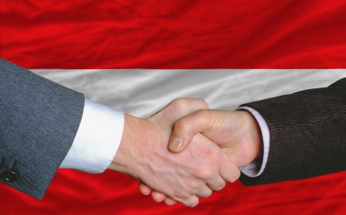 Businessmen handshake after good deal in front of austria flag clipart