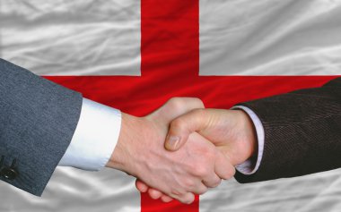 Businessmen handshake after good deal in front of england flag clipart