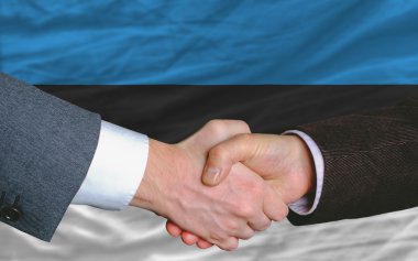 Businessmen handshake after good deal in front of estonia flag clipart