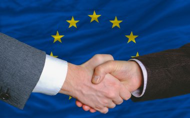 Businessmen handshake after good deal in front of europe flag clipart