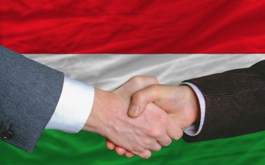 Businessmen handshake after good deal in front of hungary flag clipart