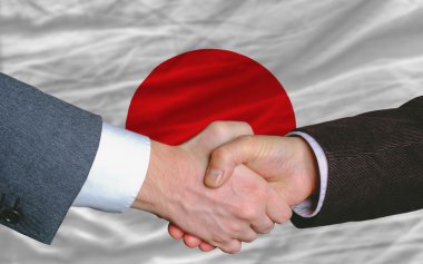 Businessmen handshake after good deal in front of japan flag clipart