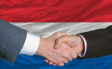 Businessmen handshake after good deal in front of netherlands fl clipart