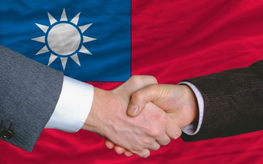 Businessmen handshake after good deal in front of taiwan flag clipart