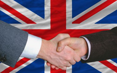 Businessmen handshake after good deal in front of uk flag clipart