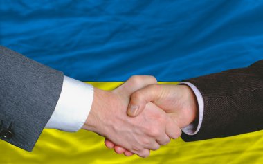 Businessmen handshake after good deal in front of ukraine flag clipart