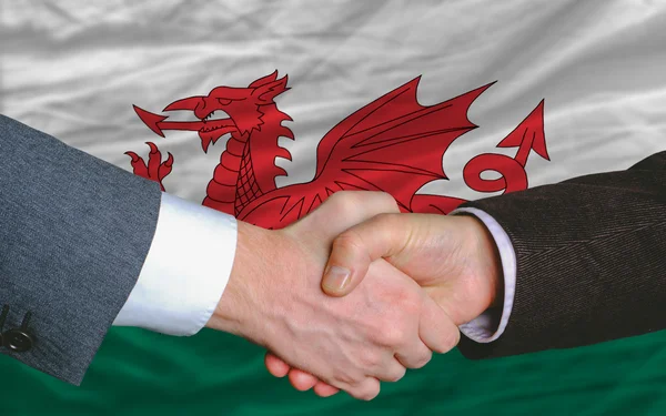 Affärsmän handskakning efter åtskilligt framför wales flagga — Stockfoto