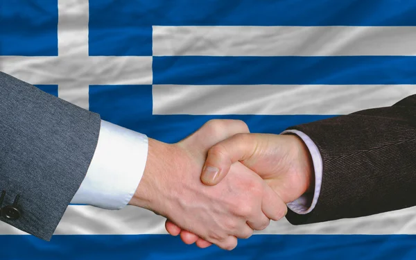 Uomini d'affari stretta di mano dopo un buon affare di fronte alla bandiera greca — Foto Stock