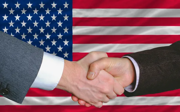 Gli uomini d'affari si stringono la mano dopo un buon affare davanti alla bandiera americana — Foto Stock