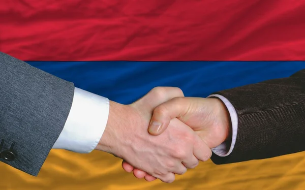 Hombres de negocios apretón de manos después de un buen trato frente a la bandera de Armenia — Foto de Stock