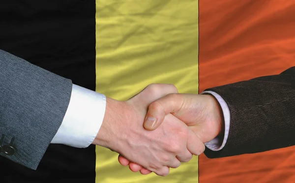Hombres de negocios apretón de manos después de un buen trato frente a la bandera de Bélgica —  Fotos de Stock